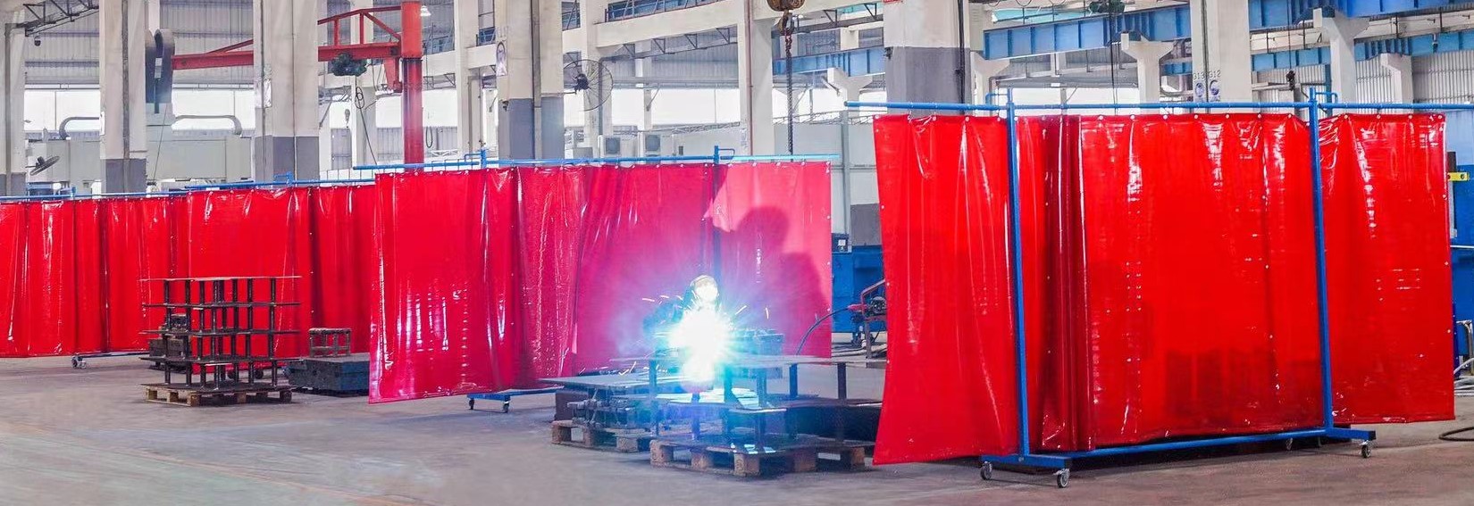man welding with PVC welding curtains in a row with partitions